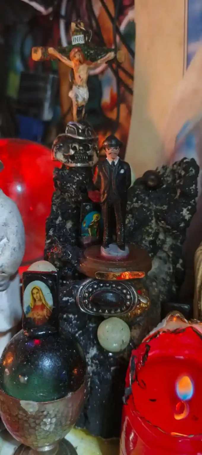 Altar esotérico con estatuilla de José Gregorio Hernández, crucifijo y velón rojo en Cúcuta.